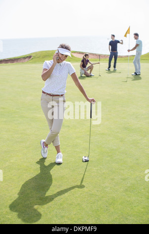 Donna che parla su telefono cellulare sul campo da golf Foto Stock