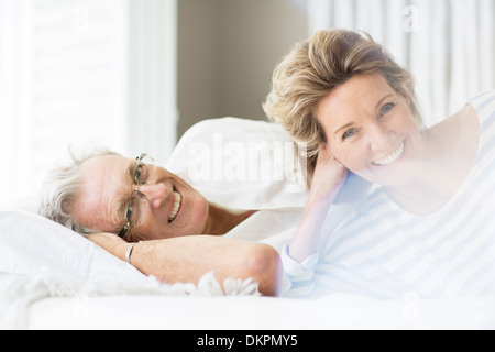 Anziana coppia sorridente sul letto Foto Stock