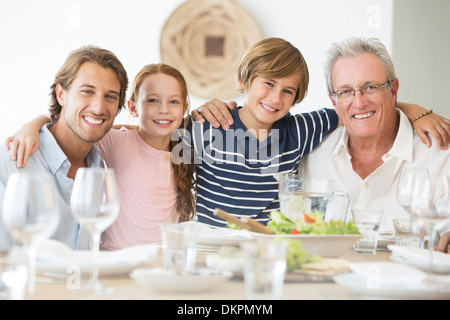 Famiglia sorridente insieme a tavola Foto Stock