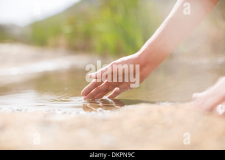 Donna immergendo le dita nelle zone rurali di stagno Foto Stock