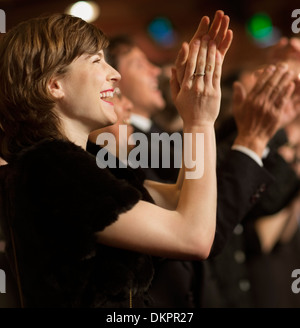 Donna felice battendo le mani in pubblico in sala Foto Stock