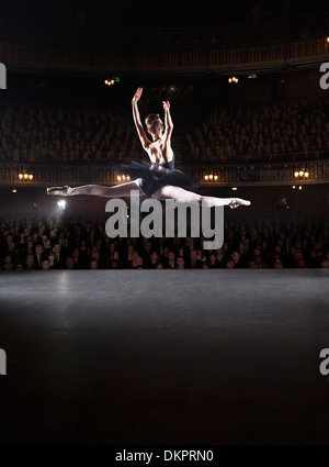 Ballerina mid-aria sul palcoscenico teatrale Foto Stock