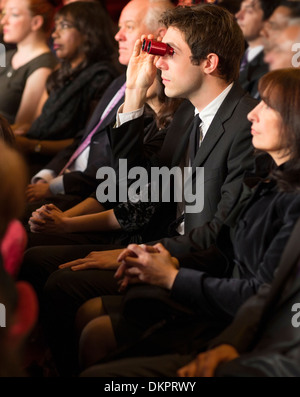 L'uomo utilizza opera bicchieri in pubblico in sala Foto Stock