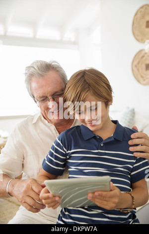 Uomo più anziano e nipote con tavoletta digitale Foto Stock