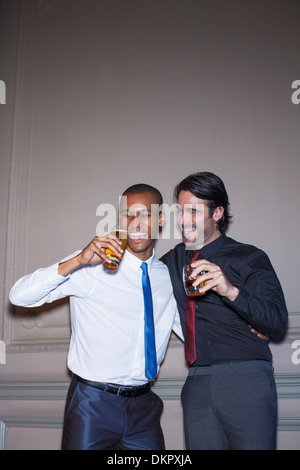 Ben vestito abbracciando gli uomini e bere birra e cocktail Foto Stock