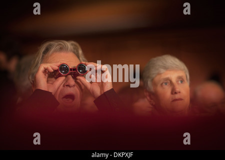 Close up uomo usando opera bicchieri in teatro Foto Stock