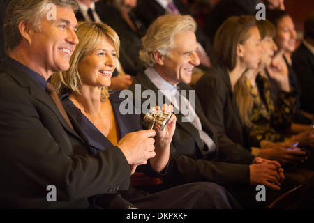 Sorridente giovane azienda opera bicchieri in pubblico in sala Foto Stock