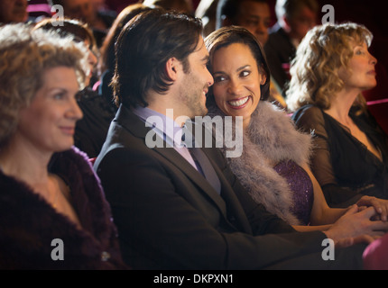 Coppia sorridente a parlare in pubblico in sala Foto Stock