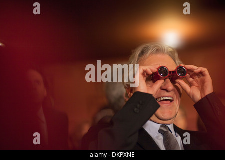 Close up uomo usando opera bicchieri in teatro Foto Stock