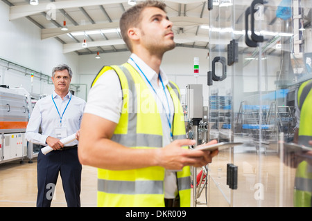 Supervisor guardando lavoratore in fabbrica Foto Stock