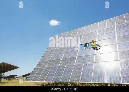 Lavoratore esaminando pannello solare nel paesaggio rurale Foto Stock