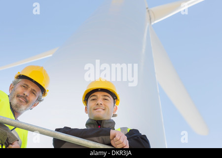 Lavoratori permanente sulla turbina eolica nel paesaggio rurale Foto Stock