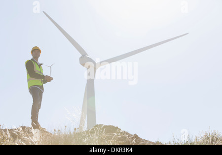 Lavoratore in piedi dalla turbina eolica nel paesaggio rurale Foto Stock