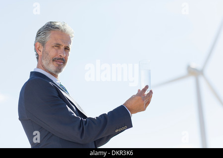 Imprenditore con un bicchiere di acqua mediante la turbina eolica Foto Stock