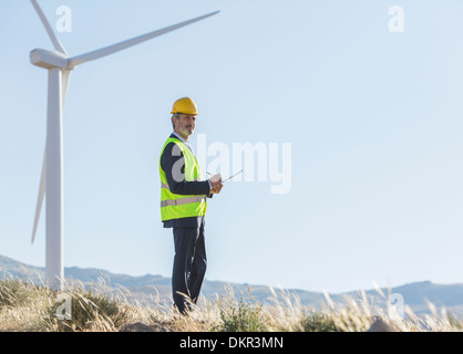 Imprenditore esaminando le turbine eoliche nel paesaggio rurale Foto Stock