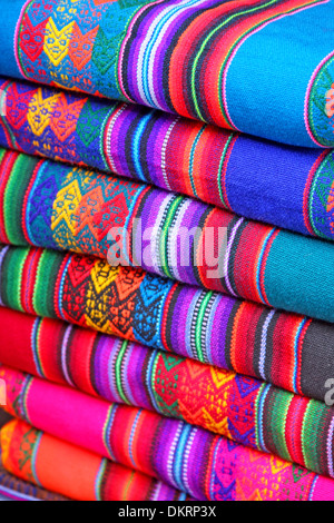 Sud Americana fatta a mano in tessuto colorato con schemi tradizionali & design. Tessuto in una pila in un mercato di Lima, Perù. Foto Stock