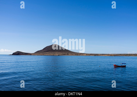 Lone rosso barca ormeggiata sul profondo blu del mare su una tranquilla giornata a El Medano, Tenerife, Isole Canarie, Spagna Foto Stock