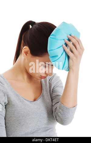 Giovane bella donna haveng è un mal di testa e tenendo il sacchetto del ghiaccio. Isolato su bianco. Foto Stock