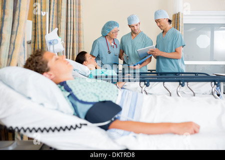 Gli infermieri a discutere di cartella paziente post-intervento chirurgico Foto Stock