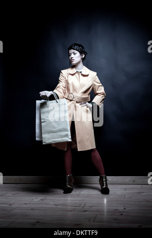 Giovane donna con le borse della spesa e la mano sul Hip Foto Stock