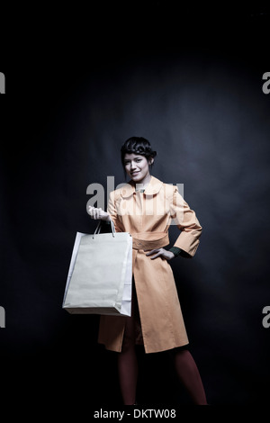 Giovane donna con le borse della spesa e la mano sul Hip Foto Stock