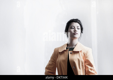 Studio Ritratto di giovane donna indossa cappotto giallo Foto Stock