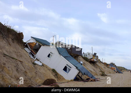 Case sulla spiaggia comprimere verso il basso sulla spiaggia o appendere in precario equilibrio sopra il bordo di dune causato da insolitamente alte maree mareggiata che lavato via la terra al di sotto di esse. Scena domenica 8 dicembre 2013 Hemsby, Norfolk Foto Stock