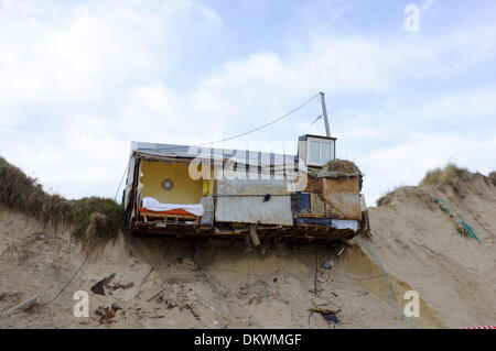 Beach home si blocca in precario equilibrio sopra il bordo delle dune sulla spiaggia come insolitamente alta marea surge storm lavato via la terra sotto di esso. Scena domenica 8 dicembre 2013. Hemsby, Norfolk Foto Stock
