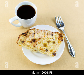 Primo piano top view foto di italiani freschi fette di torta su una piastra bianca lungo con forcella sul lato e una tazza di caffè nero Foto Stock