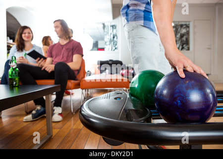 Man Picking palla da bowling dalla cremagliera Foto Stock