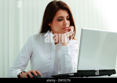 Giovane imprenditrice nelle cuffie al lavoro su un notebook in ufficio Foto Stock