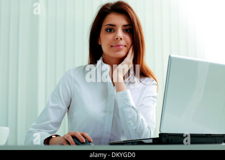 Giovane imprenditrice nelle cuffie al lavoro su un notebook in ufficio Foto Stock