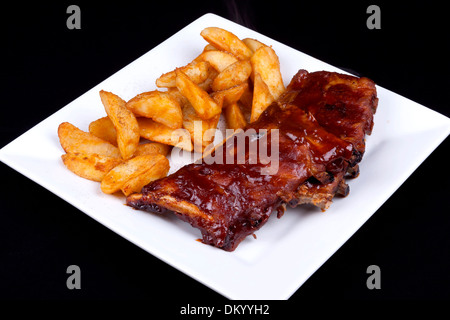 BBQ Ribs con spicchi di patate su una piastra bianca. Foto Stock