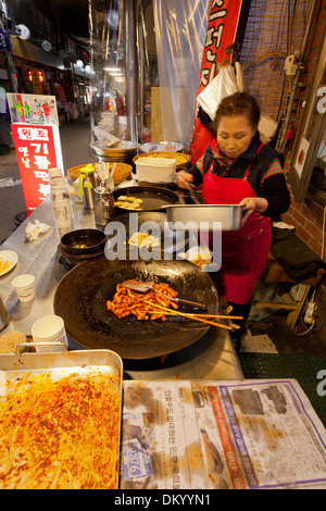 Donna fare Tteokbokki (topokki) al mercato tradizionale - Seoul, Corea del Sud Foto Stock