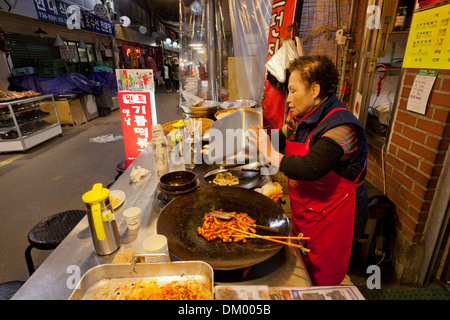 Donna fare Tteokbokki (topokki) al mercato tradizionale - Seoul, Corea del Sud Foto Stock