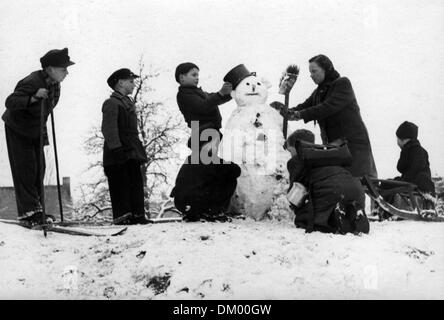 I bambini costruire un pupazzo di neve a Berlino, in Germania, in inverno 1950. Foto: Eva Richter Foto Stock