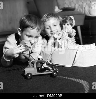 Una ragazza e un ragazzo di giocare con i loro regali di Natale - una controllata in remoto auto giocattolo e una bambola in una borsa di trasporto non datato fotografia dai primi anni sessanta ies. Foto: Heinz Junge Foto Stock