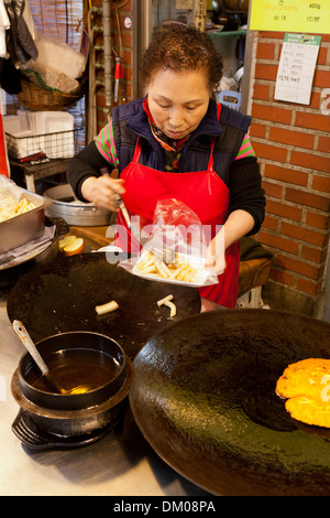 Donna fare Tteokbokki (topokki) al mercato tradizionale - Seoul, Corea del Sud Foto Stock