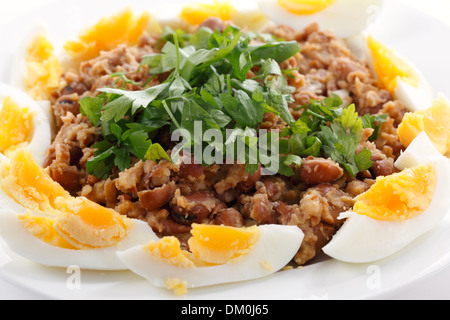 Fallo egiziano - o ful medames - su una piastra garneshed con fette di uova sode e il prezzemolo. Foto Stock