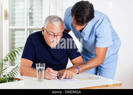 Infermiere Senior aiuta l uomo a risolvere puzzle Foto Stock
