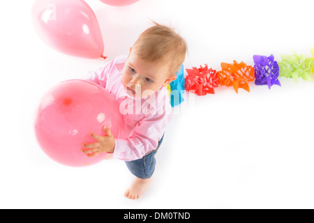 Allegro baby boy a piedi con palloncino rosa nelle sue mani Foto Stock