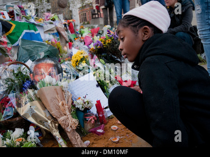 Come un omaggio a Nelson Mandela a bambini e adulti in lutto per la sua morte e portato fiori & messaggi e candele accese sotto il suo Foto Stock