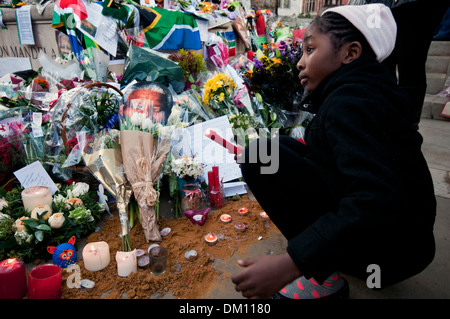 Come un omaggio a Nelson Mandela a bambini e adulti in lutto per la sua morte e portato fiori & messaggi e candele accese sotto il suo Foto Stock