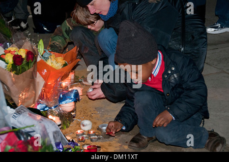 Come un omaggio a Nelson Mandela a bambini e adulti in lutto per la sua morte e portato fiori & messaggi e candele accese sotto il suo Foto Stock