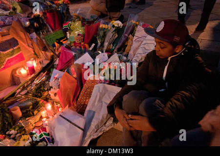 Come un omaggio a Nelson Mandela a bambini e adulti in lutto per la sua morte e portato fiori & messaggi e candele accese sotto il suo Foto Stock