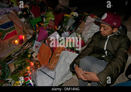 Come un omaggio a Nelson Mandela a bambini e adulti in lutto per la sua morte e portato fiori & messaggi e candele accese sotto il suo Foto Stock