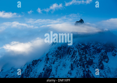 L'Aiguille du Midi che appare attraverso le nuvole, Mont Blanc, les Alpi, Alta Savoia, Francia Foto Stock