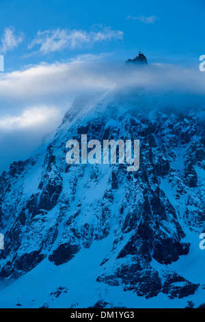 L'Aiguille du Midi che appare attraverso le nuvole, Mont Blanc, les Alpi, Alta Savoia, Francia Foto Stock