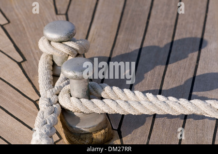 Dettaglio di una barca in teak deck: funi legate a un bitt Foto Stock