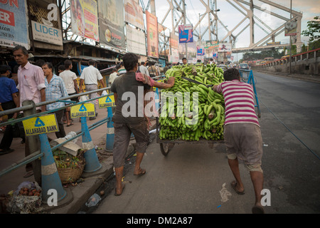 Street carrello pieno di banane attraversando il ponte di quella di Howrah a Calcutta (Kolkata), India Foto Stock